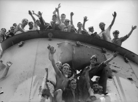 Cheering sailors look out through the hole created by the Bande Nere’s shell in HMAS Sydney's funnel.